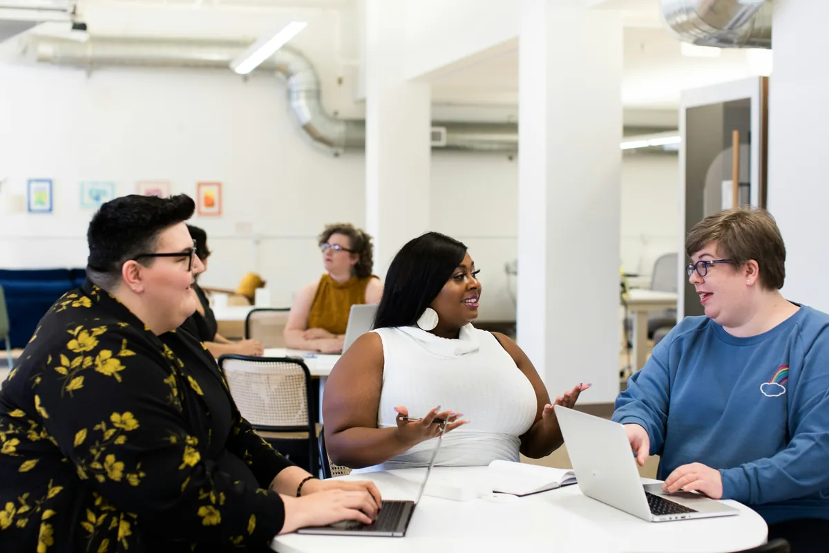A team reviewing work together on laptops in a bright office