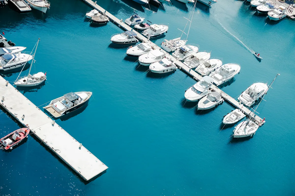 White boats in slips along a concrete pier over turquoise water