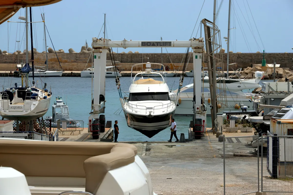 A travel lift hauling a motor yacht at a boatyard ramp