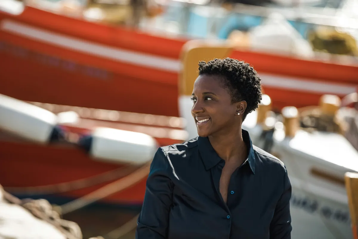 A smiling dockmaster standing among moored boats