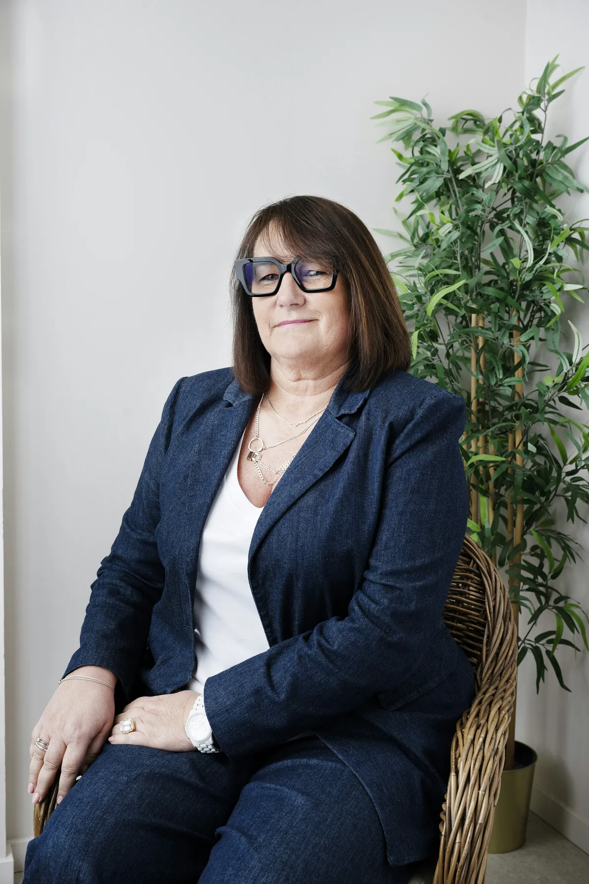 A finance director in a navy suit seated by a white wall