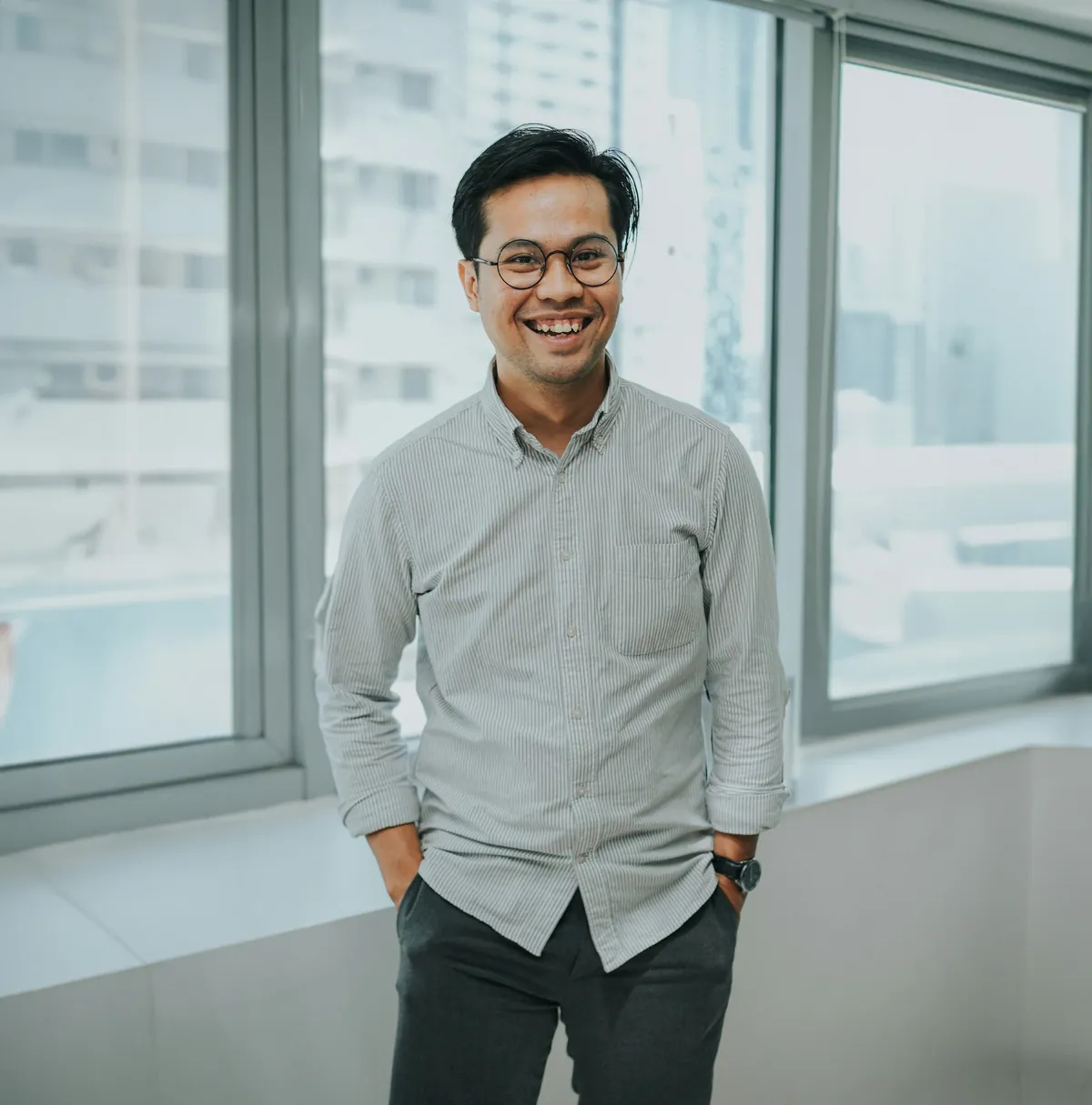 A smiling IT director with glasses by bright office windows