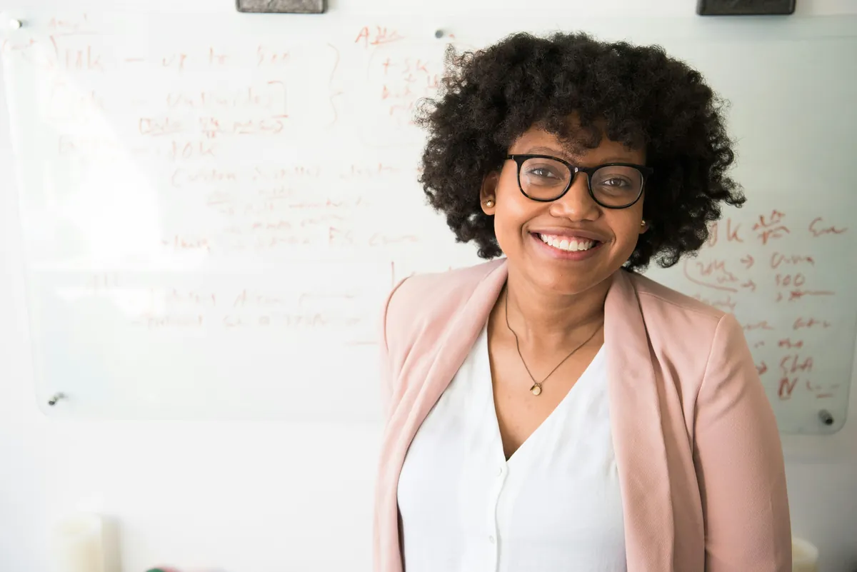 A smiling school business manager in a pink blazer