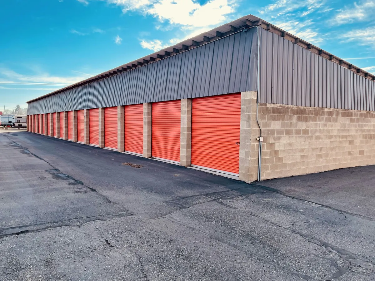 A row of roll-up storage doors along a paved drive