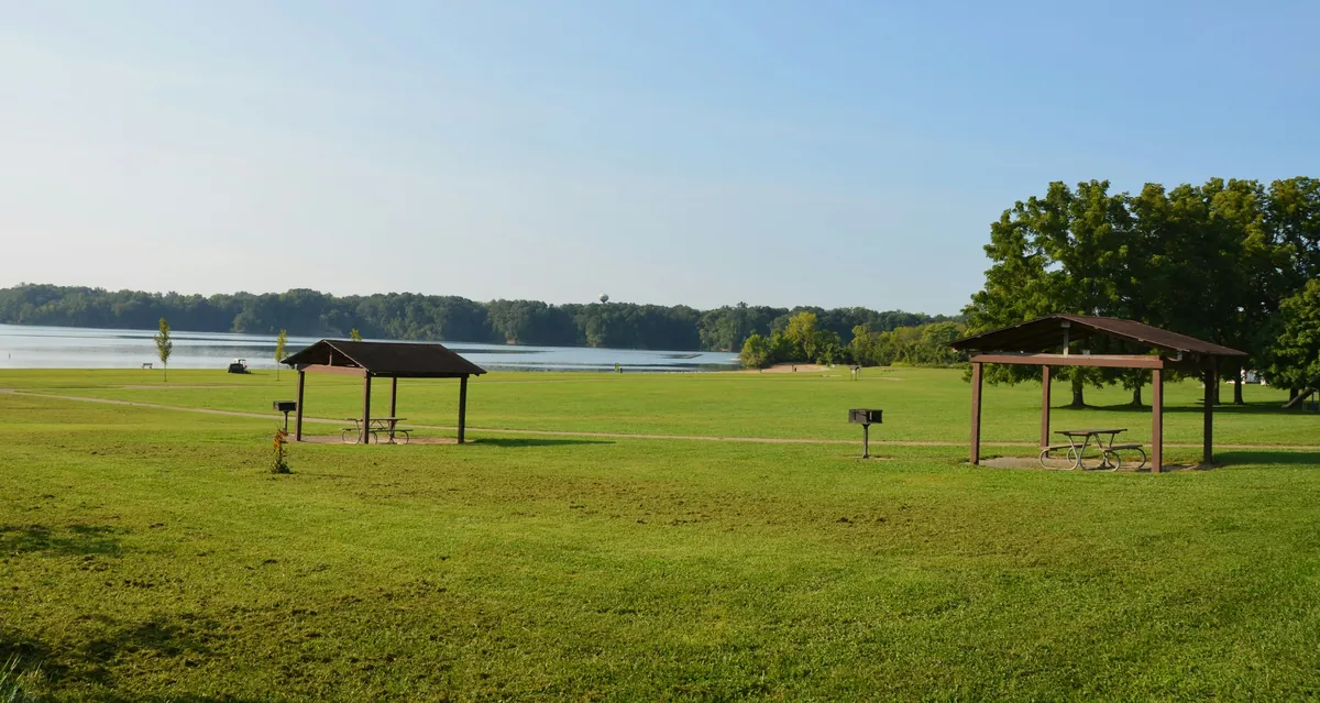 Two wooden picnic shelters in a lakeside park